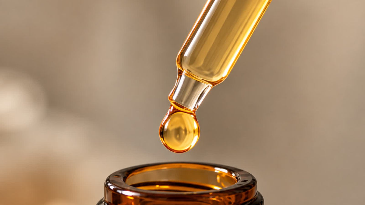 A single drop falling from a glass dropper into an amber bottle