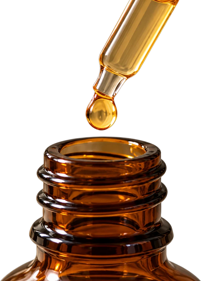 A drop of amber liquid falling from a glass dropper into a bottle